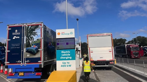 Shell Recharge charging hub for electric vehicles with sign reading “Electric vehicle charging Up to 400 kW,” positioned between two lorries.