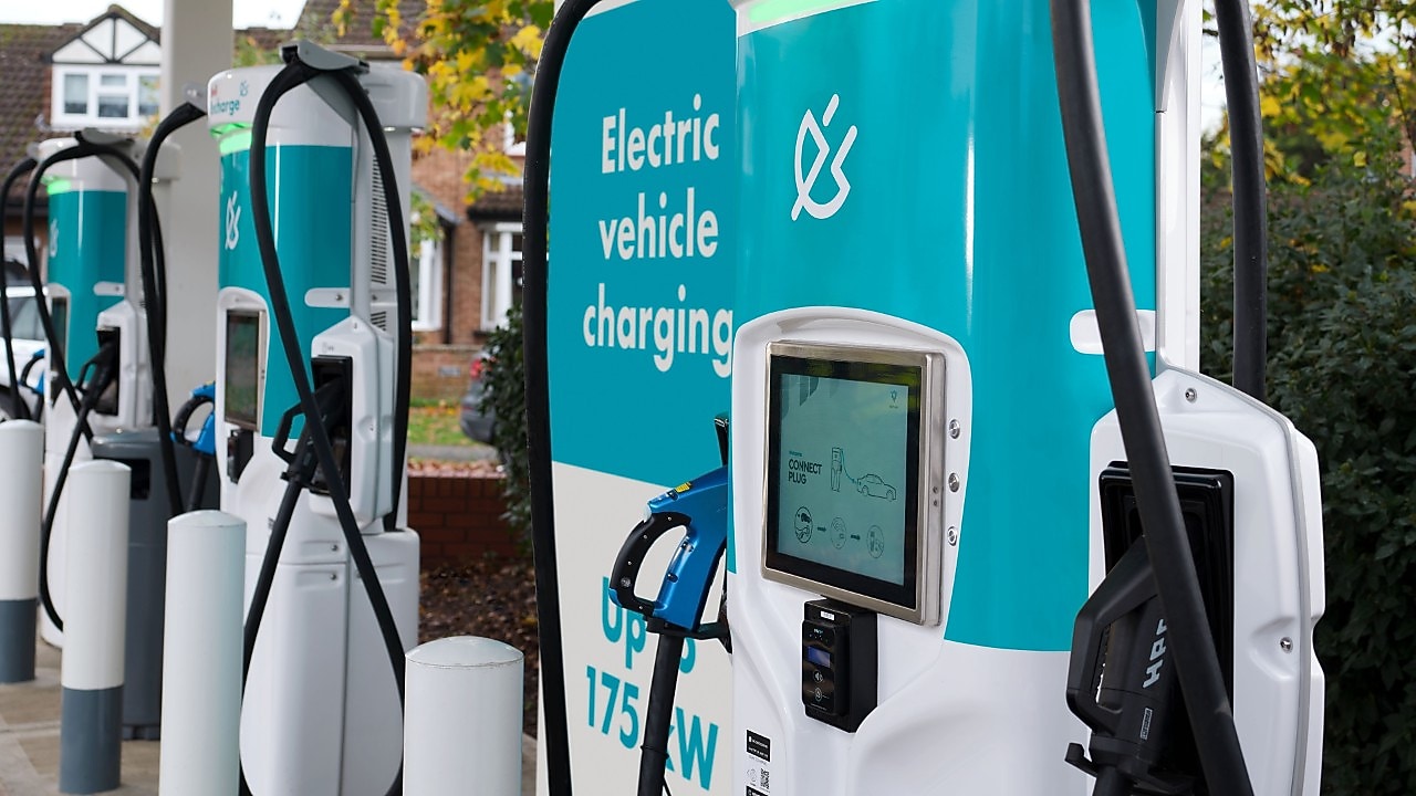Electric vehicle charging stations with teal and white colour, featuring digital screens and charging cables.