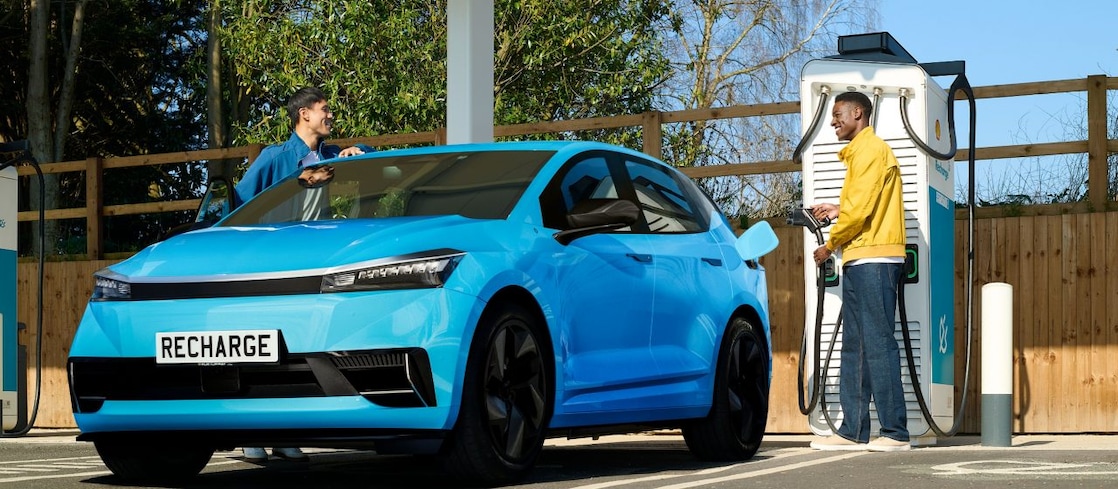 Two men standing and talking next to a blue electric vehicle charging.