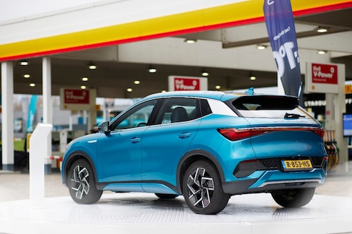 A blue car parked next to a Shell Garage Station