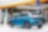 A blue car parked next to a Shell Garage Station