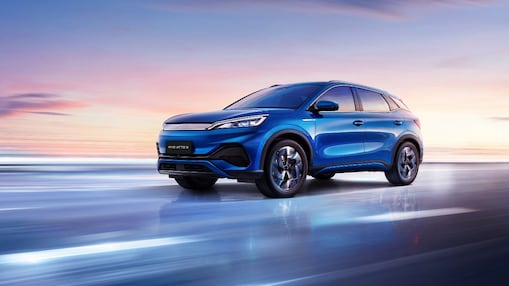 A blue car driving on a blue road with a pink sunset sky