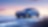 A blue car driving on a blue road with a pink sunset sky