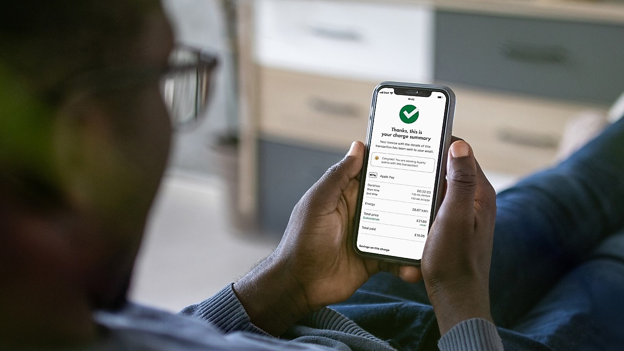 A person holding a phone,  open on the Shell App