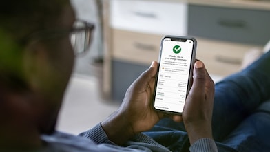 A person holding a phone,  open on the Shell App