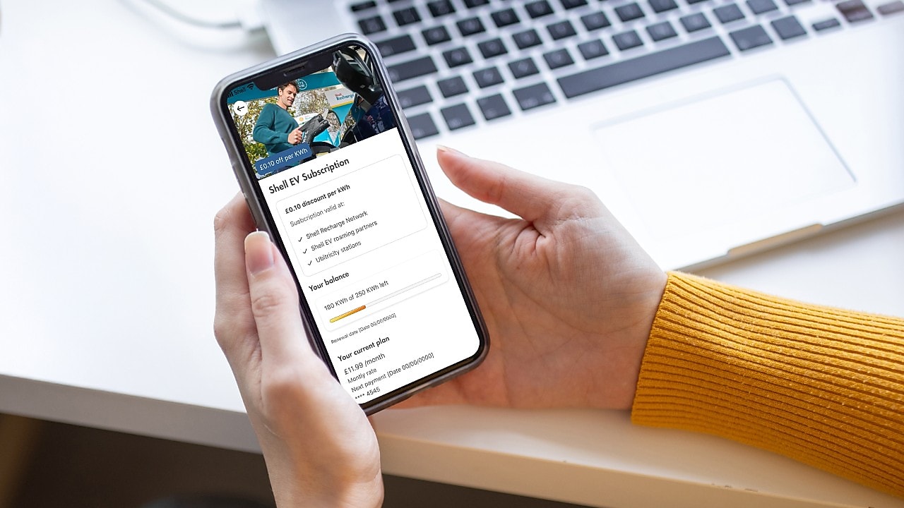 A person holding a phone,  open on the Shell App