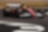 A red Scuderia Ferrari HP Formula 1 race car with prominent Shell and Ferrari logos is captured mid-turn on a racetrack. The car has large tires, aerodynamic wings, and a driver wearing a yellow helmet. The background shows part of the track and grass.