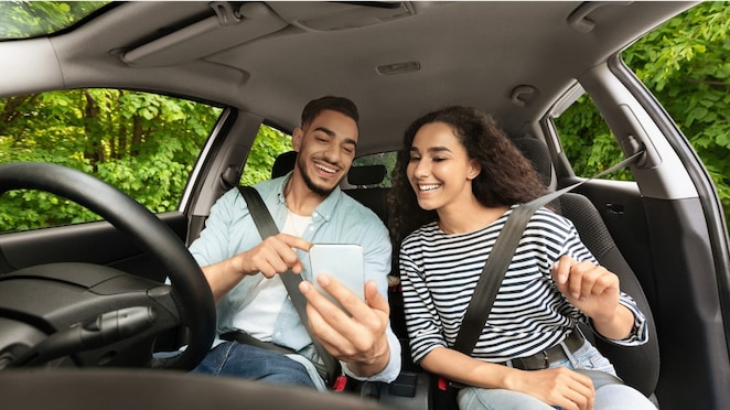 Man and woman looking at a phone in a stationary car