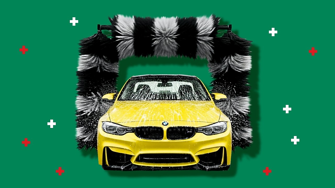 A bright yellow car covered in soap foam passes through an automated car‑wash machine with large black‑and‑white rotating brushes, set against a green background with small red and white graphic plus symbols.
