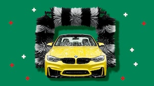 A bright yellow car covered in soap foam passes through an automated car‑wash machine with large black‑and‑white rotating brushes, set against a green background with small red and white graphic plus symbols.