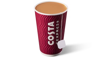 Image shows a Costa Express paper cup filled with a freshly brewed tea with milk, and a tea bag tag hanging over the rim of the cup.