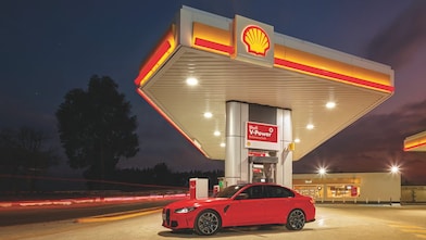 A red BWM M3 parked on a Shell Forecourt during dusk